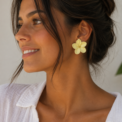 Brincos florais amarelos usados por mulher com camisa branca e cabelo preso