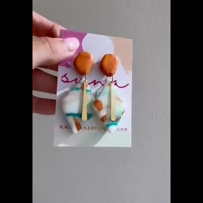 Mão segurando cartão com brincos coloridos