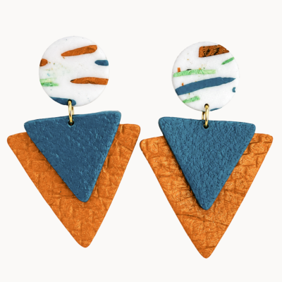 Brincos triangulares e redondos em azul, laranja e branco com detalhes coloridos e textura.
