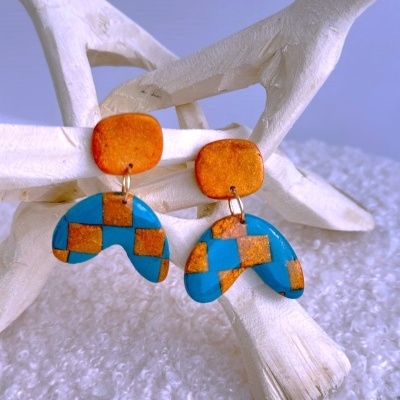 Brincos geométricos em laranja e azul com padrão quadriculado