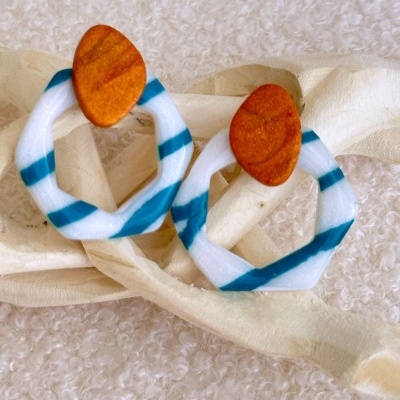 Brincos laranja e branco com riscas azuis sobre tecido bege