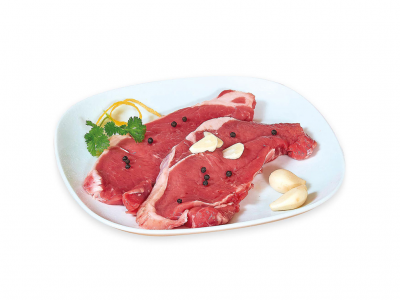 Duas fatias de carne crua vermelha num prato branco com alho, pimenta preta e salsa