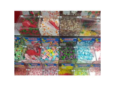 Recipientes transparentes com gomas coloridas HARIBO e pinças vermelhas para servir