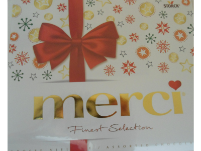 Embalagem de chocolates Merci com laço vermelho e estrelas coloridas