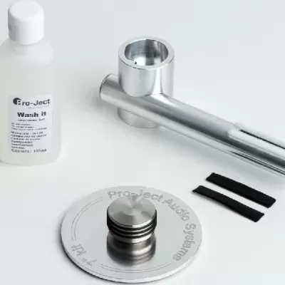 Peças metálicas cromadas e frasco Pro-Ject Wash it sobre fundo claro