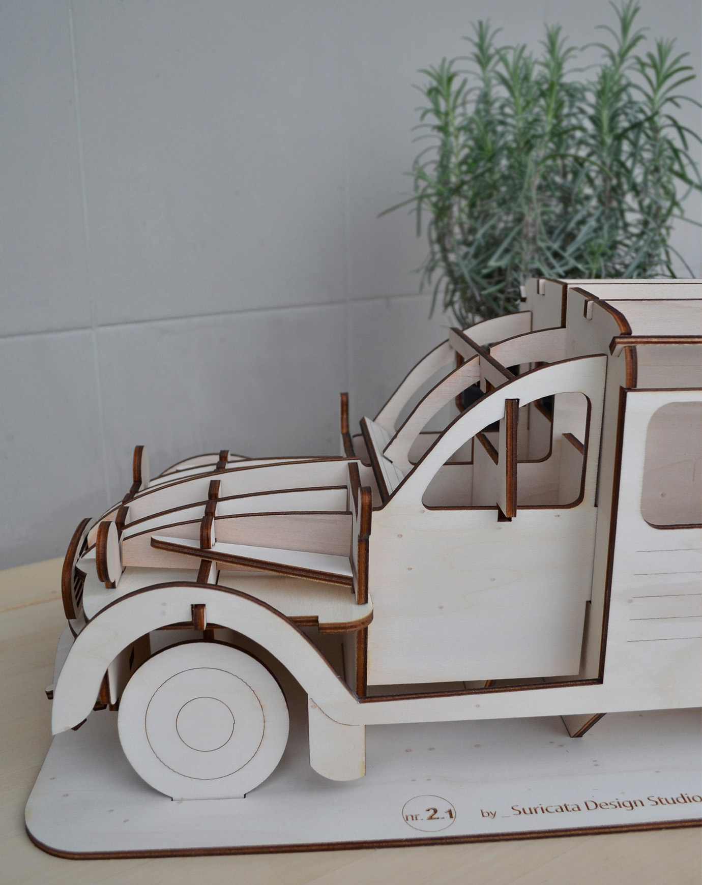 MODEL NR.2.1 VAN - XL Modelo de carrinha de madeira clara com peças encaixadas e planta ao fundo
