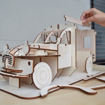 Modelo de carro de madeira desmontável com detalhes recortados numa mesa