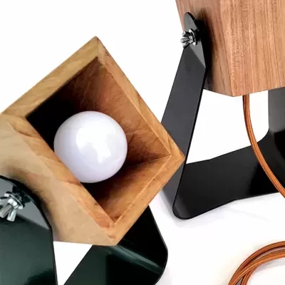 Candeeiros de mesa em madeira clara com base metálica preta e lâmpada branca visível