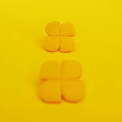 Quatro comprimidos amarelos em forma de cruz sobre fundo amarelo com reflexo.