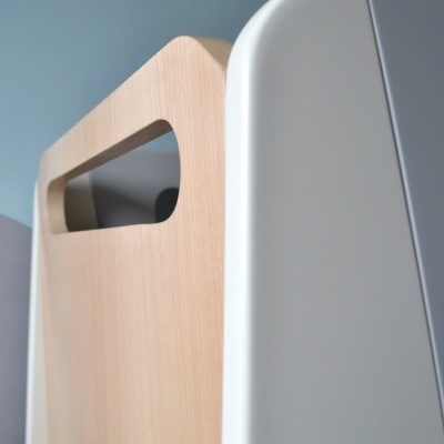 Detalhe de móvel em madeira clara e branco junto a parede azul claro e cama