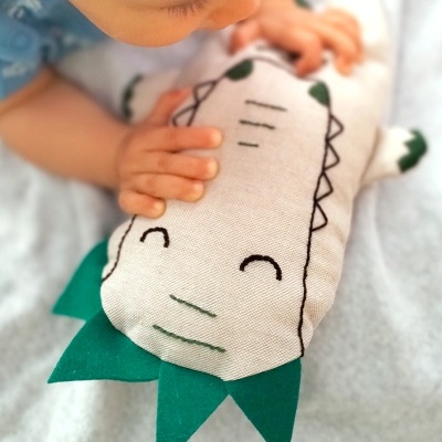 Pelúcia de crocodilo branca com detalhes verdes nas extremidades