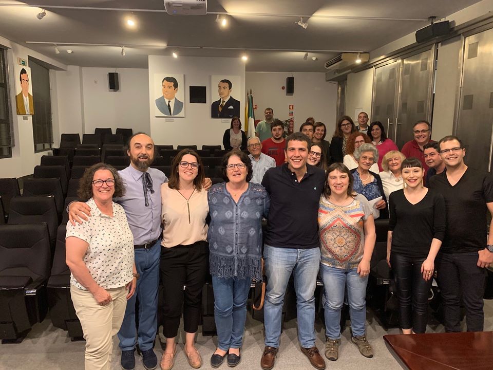 Grupo de pessoas em sala de conferências com cadeiras e retratos na parede
