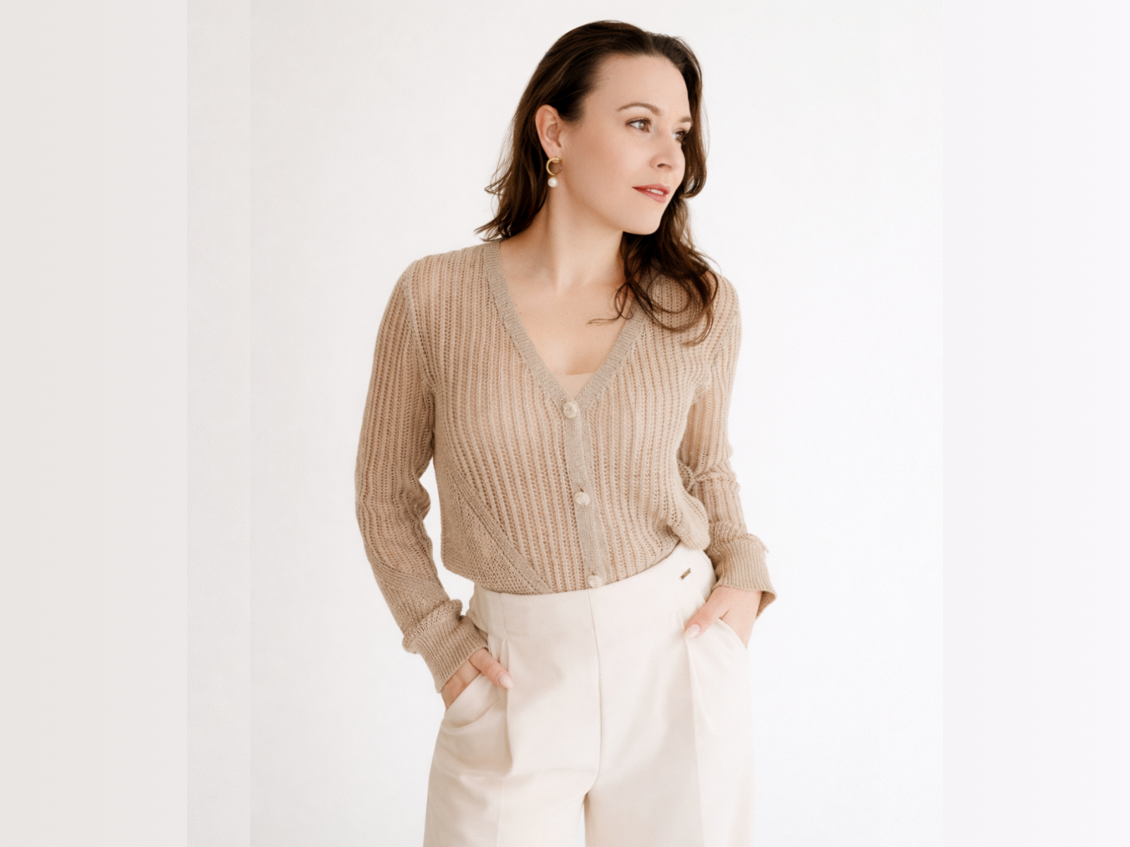 Mulher a usar cárdigan bege e calças creme em fundo branco