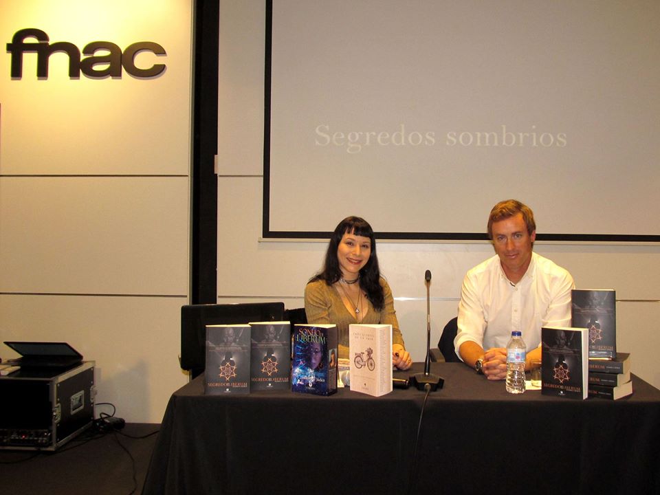 Apresentação FNAC Faro - Fórum Algarve Duas pessoas sentadas atrás de uma mesa com livros numa apresentação na Fnac
