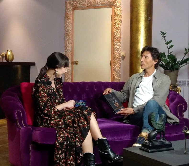 Sofá roxo de veludo com mulher e homem sentados