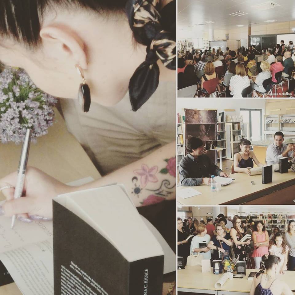 Evento em biblioteca com mulher a assinar livros e público presente