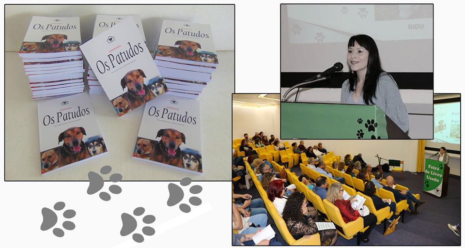 Lançamento Antologia "Os Patudos" Livros 'Os Patudos' com cães na capa, mulher a falar num pódio e audiência num auditório