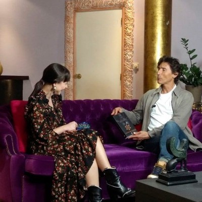 Sofá roxo de veludo com mulher e homem sentados