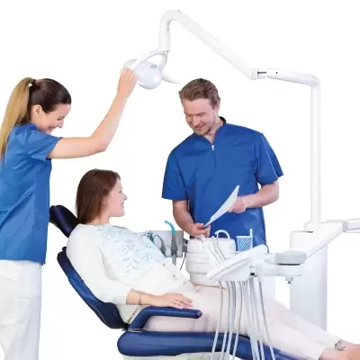 Cadeira dentária azul com luz e equipamento, paciente e profissionais de saúde