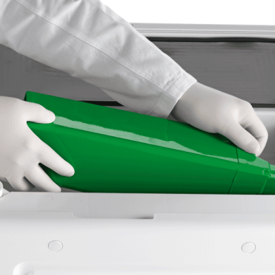 Mãos com luvas a segurar cartucho verde em máquina branca
