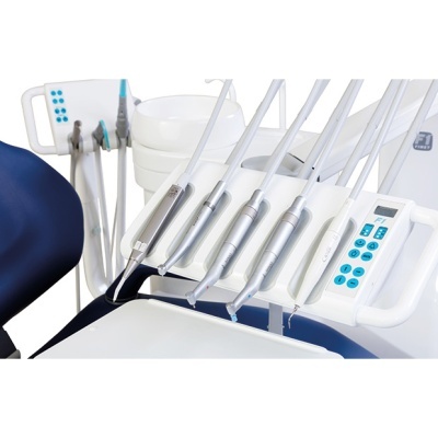 Instrumentos dentários em suporte branco junto a cadeira dentária azul.