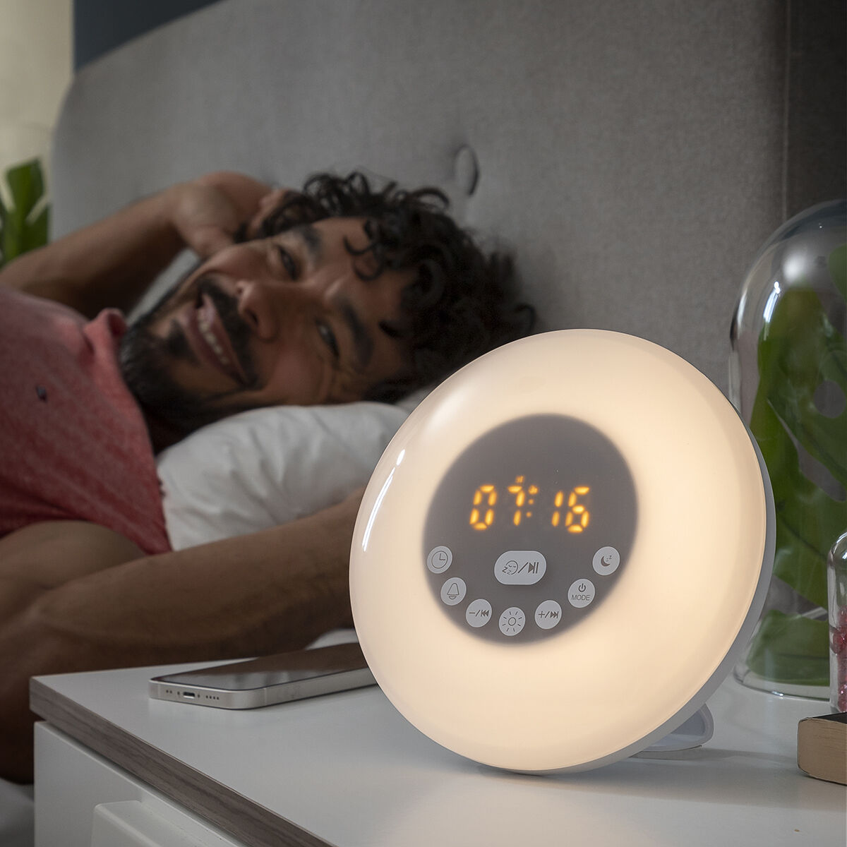 Despertador Amanhecer Recarregável com Alta voz Sunrilk InnovaGoods Despertador digital redondo com luz LED e visor 07:16 numa mesa ao lado de smartphone