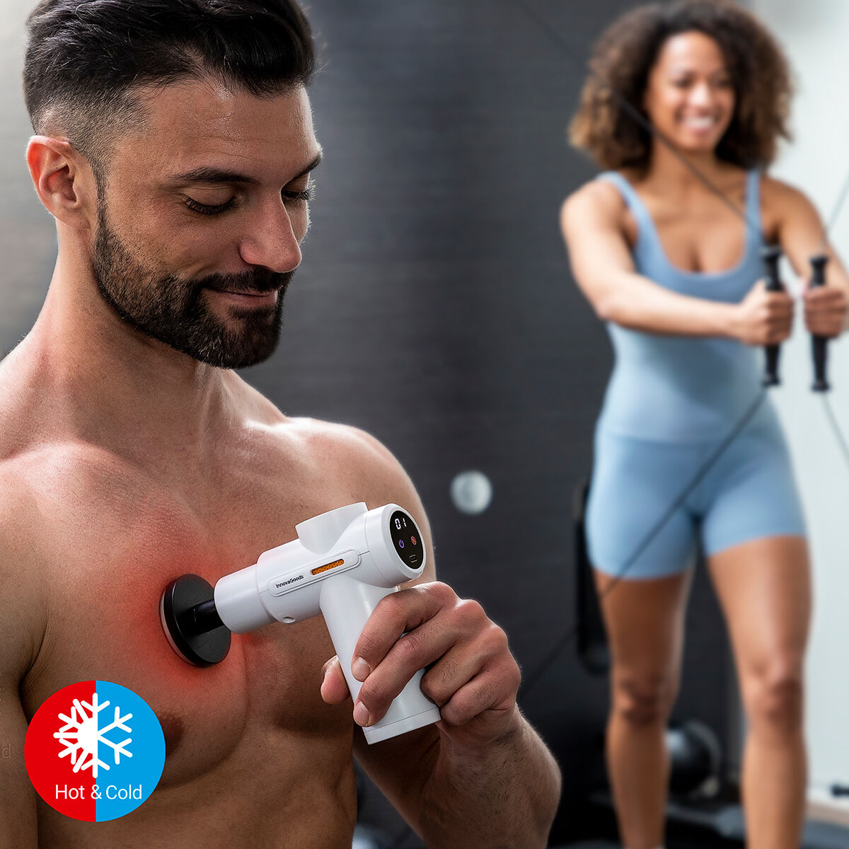 Pistola de Massagem Muscular com Frio e Calor Hokgun InnovaGoods Homem a usar pistola de massagem branca no peito com mulher a exercitar-se ao fundo