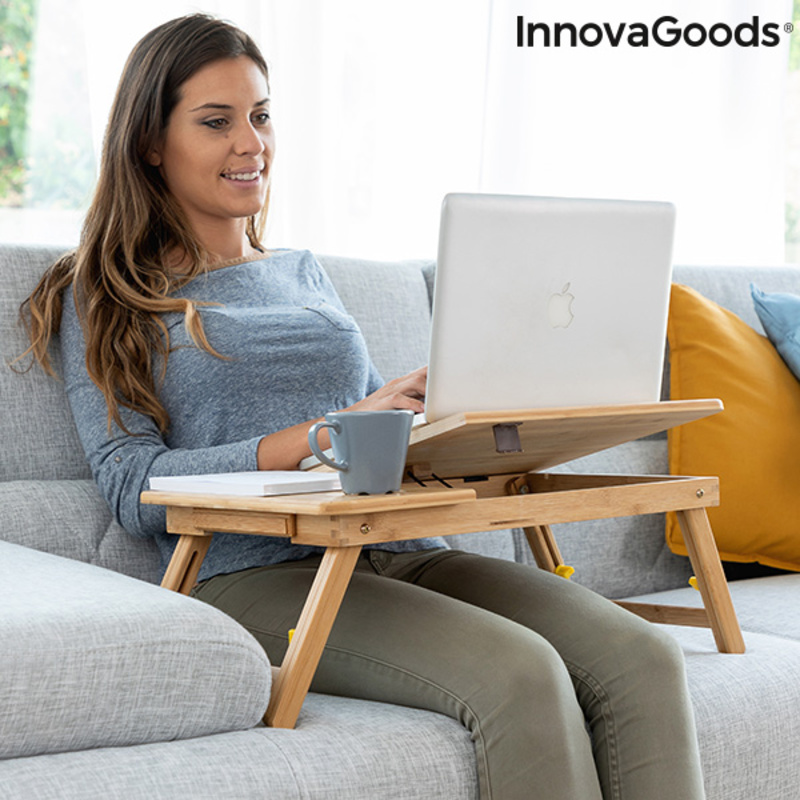 Mesa Auxiliar Dobrável de Bambu Lapwood InnovaGoods Mulher sentada no sofá a usar portátil numa mesa de bambu com caneca e livro