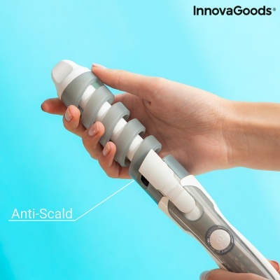 Aparelho modelador de cabelo cinza e branco segurado por mão, fundo azul