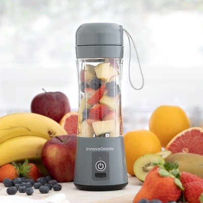 Liquidificador portátil InnovaGoods cinza com frutas dentro sobre mesa com frutas variadas ao redor