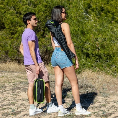 Duas pessoas ao ar livre com roupas casuais e bolsas pretas.