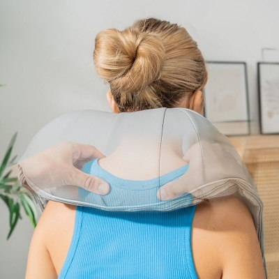 Travesseiro de pescoço cinza em interior com pessoa usando top azul