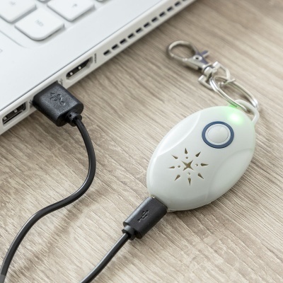 Dispositivo eletrônico branco com cabo USB ligado a laptop num tampo de madeira