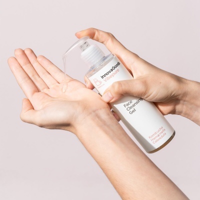 Mãos a usar gel de limpeza facial InnovaGoods de embalagem branca com tampa de bomba.