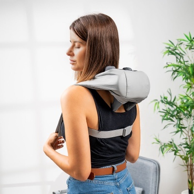 Mulher de costas com mochila cinzenta em ambiente interior com planta e cadeira