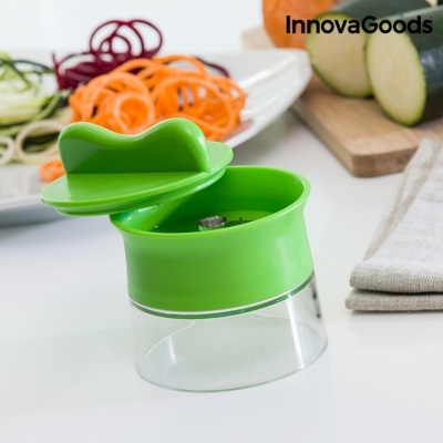 Triturador manual verde com recipiente transparente em cozinha com legumes cortados