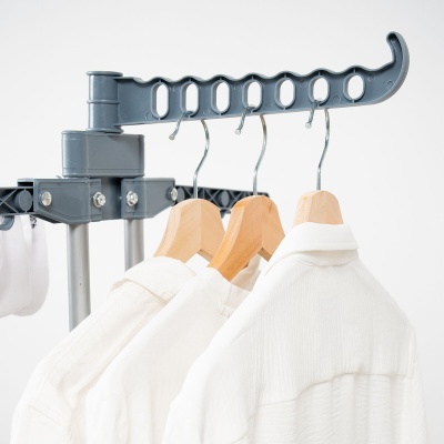 Suporte articulado cinzento com camisas brancas em cabides de madeira