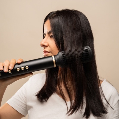 Mulher a usar escova elétrica preta para cabelo