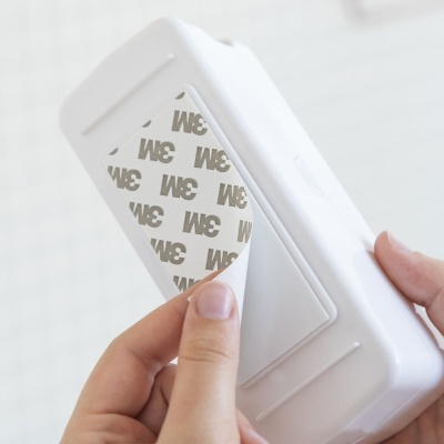 Dispositivo branco com fita adesiva 3M sendo destacada por mão