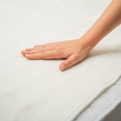 Mão pousada sobre tecido branco liso e suave