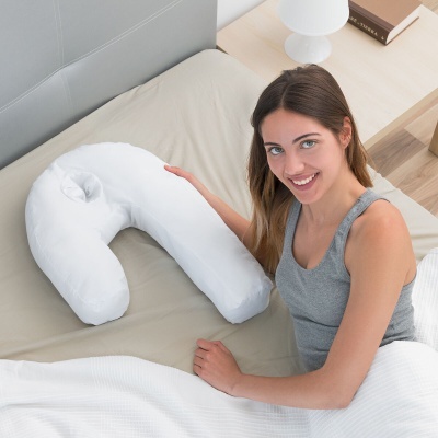 Travesseiro em forma de U branco com mulher sentada na cama