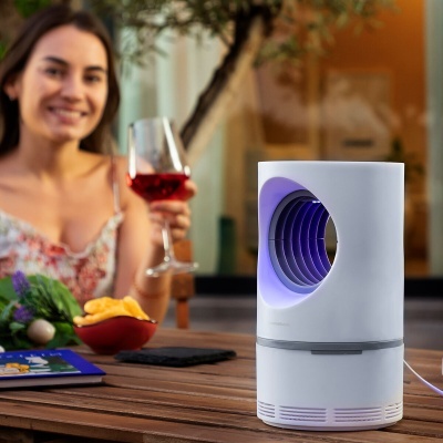 Dispositivo eletrónico branco com luz azul numa mesa com vinho e batatas fritas