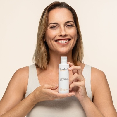 Mulher a segurar um frasco de soro facial hidratante e suavizante