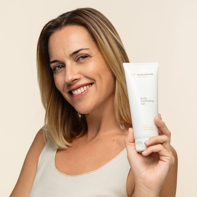 Mulher segura tubo branco de gel exfoliante corporal