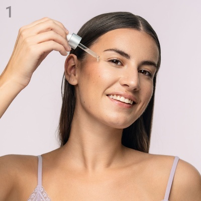 Mulher a aplicar sérum facial com conta-gotas