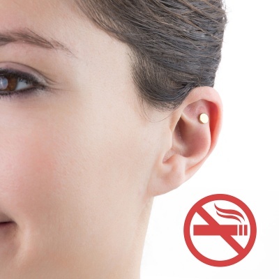 Orelha feminina com brinco dourado circular e símbolo de proibição de fumar