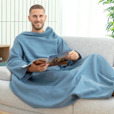 homem sentado no sofá com manta wearable azul claro lendo revista