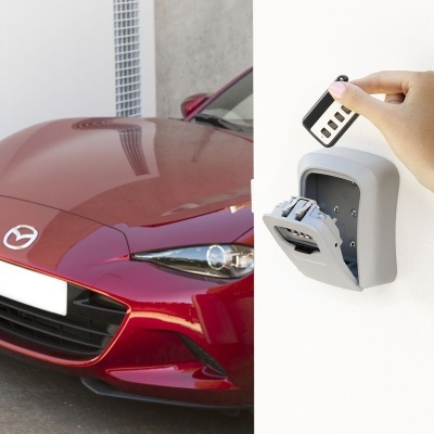 Carro vermelho Mazda e caixa de chaves cinza na parede com mão a abrir