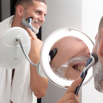 Homem a fazer a barba com espelho iluminado de braço flexível