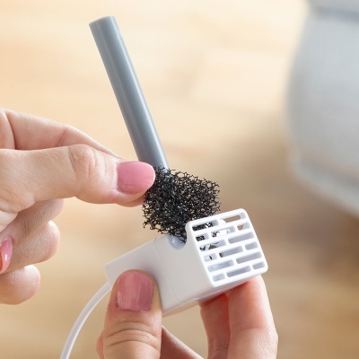 Dispositivo branco pequeno com esponja preta e tubo cinza nas mãos